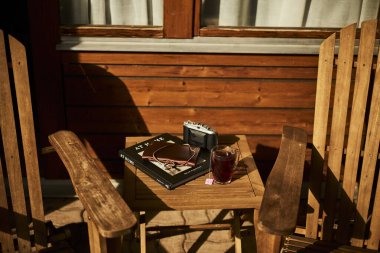 İsviçre yazında dağ manzaralı sandalyeler, çay, kahve ve kitapların yer aldığı bir otel balkonu ve göl manzarası. Sahne, rahat bir dağlık yaşam tarzı, huzurlu bir atmosfer ve rahat bir seyahat deneyimi yakalıyor. Konseptler için uygun