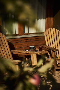 İsviçre yazında dağ manzaralı sandalyeler, çay, kahve ve kitapların yer aldığı bir otel balkonu ve göl manzarası. Sahne, rahat bir dağlık yaşam tarzı, huzurlu bir atmosfer ve rahat bir seyahat deneyimi yakalıyor. Konseptler için uygun