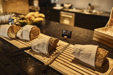 Otelin kahvaltı masasına dilimlenmeye hazır taze pişmiş İsviçre ekmeği. Sahne misafirperverliği, geleneksel alp mutfağını ve rahat bir kahvaltı deneyimini yansıtıyor. Seyahat, turizm, kahvaltı, oteller ve Avrupa 'ya uygun konseptler