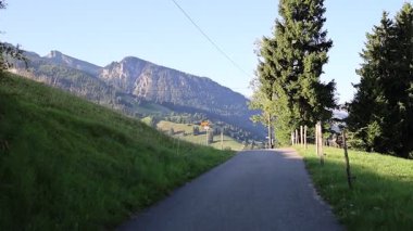 İsviçre 'nin manzaralı dağ yolu güneşli bir yaz gününde dağ manzarası ve ışıl ışıl bir göl sunuyor. Sahne, huzurlu manzaralar, seyahatler ve İsviçre Alplerinin güzelliğini yansıtıyor. Turizm, macera ve Avrupa dağları kavramları için uygun