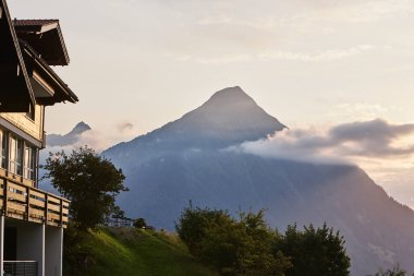 Yeşil dağ manzaraları, dağ zirveleri ve açık gökyüzünün yer aldığı İsviçre Alpleri 'nin yaz manzarası. Görüntü, seyahat, turizm, yürüyüş ve Avrupa doğa kavramları için uygun, doğal güzellik, sükunet ve açık hava macerası taşır..