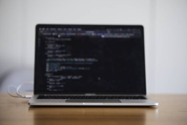 Modern ofis ortamında programlama için kullanılan bir dizüstü bilgisayar. Sahne kodlamayı, yazılım geliştirmeyi, üretkenliği ve çağdaş çalışma alanı kurulumunu ön plana çıkarıyor. Teknoloji, bilişim işi, uzaktan çalışma, ofis hayatı ve dijital için uygun