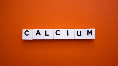 Kalsiyum Kelimesi Beyaz Harf Döşemeleri ile Yazılıyor Turuncu Arkaplan