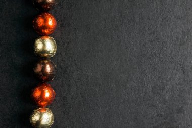 Çok renkli folyoya sarılıp siyah arka planda fotokopi alanı olan çikolatalı şekerler. Düz yatış, üst görünüm