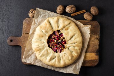 Elmalı ev yapımı galette turtası, yaşlı böğürtlenleri ve taşralı ahşap tahtada taze ahududu ile süslenmiş ceviz. Düz yatış, üst görünüm