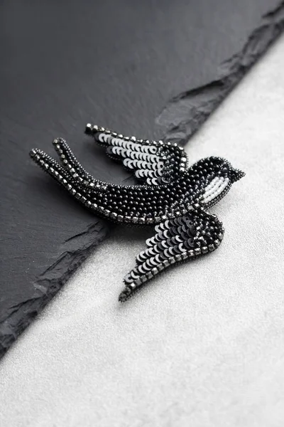 Seed bead embroidered brooch in a shape of black swallow bird on black background
