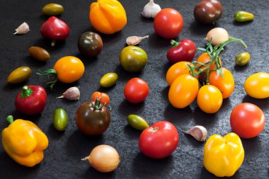Siyah arka planda çeşitli renkli taze domatesler.