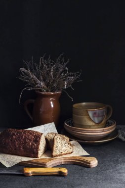 Tahta bir tahtanın üzerinde ayçiçeği ve keten tohumlu ekmek. Arkaplanda seramik çanak çömlek.