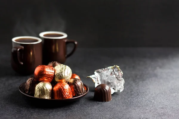 Doces Chocolate Envoltos Folha Multicolorida Uma Placa Duas Xícaras Café — Fotografia de Stock
