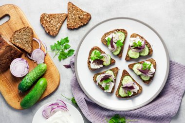 Kızarmış ekmekli kanepeler, ayçiçeği ve keten tohumları, feta peyniri, salatalık ve soğan.