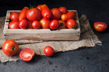 Siyah zemin üzerinde tahta kutuda taze kırmızı domatesler..