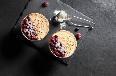 Ryazhenka (mayalanmış pişmiş süt) taze böğürtlenlerle süslenmiş cam kaselerde krema. Düz yatış, üst görünüm.