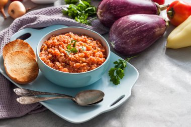 Mavi kasede patlıcan havyarı ve arka planda taze sebzeler..