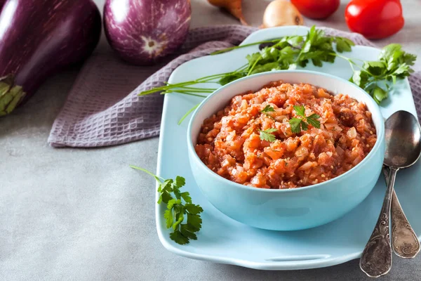 Mavi kasede patlıcan havyarı ve arka planda taze sebzeler..