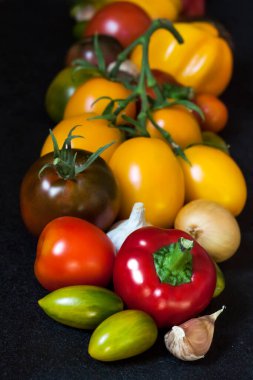 Siyah arka planda çeşitli renkli taze sebzeler.