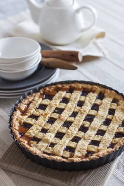 Yeni pişmiş kafes turtası istiflenmiş tabaklar, kaseler ve beyaz çaydanlığın yanında ev yapımı tatlı sahnesi yaratıyor..