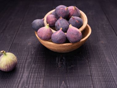 Ahşap kasede olgun incir sürüsü, siyah ahşap arka planda karanlık kasede yakalanmış.