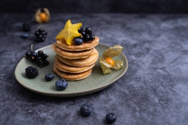 Yeşil tabakta böğürtlenli krep yığını ve bal.