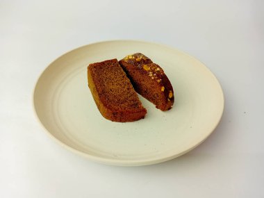 Peynir soslu bir parça muzlu kek, ikiye bölünmüş, yuvarlak bir tabakta servis edilmiş, beyaz bir arka planda izole edilmiş..