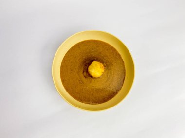 Beyaz arka planda izole edilmiş, yuvarlak bir tabakta servis edilen fıstık soslu Batagor. Endonezya yemekleri.