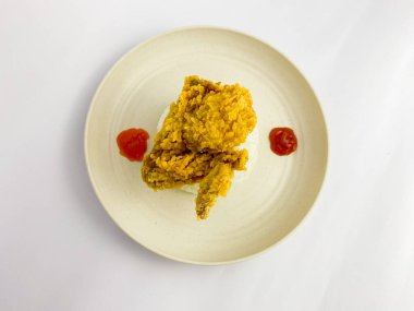 Fried chicken wing with cooked rice served on a round plate with tomato and chili sauces, isolated on white background.