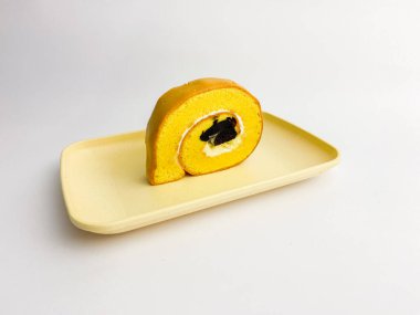 Rolltart moka with vanilla cream served on a square plate, isolated on white background.