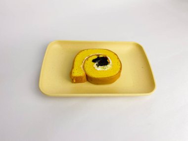 Rolltart moka with vanilla cream served on a square plate, isolated on white background.