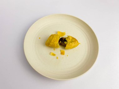 Pisang Molen ya da Banana Molen ikiye bölünmüş, yuvarlak tabakta servis edilmiş, beyaz arka planda izole edilmiş..