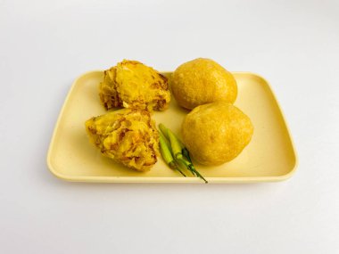 Bala-bala ve tahu bulat bir kare tabakta yeşil biber ile servis edilir, beyaz arka planda izole.