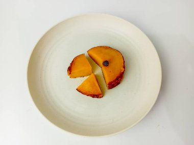 Kue Lumpur ya da Mud keki parçalara ayrılmış. Ana malzemeler olarak hindistan cevizi sütü, patates, buğday unu ve yumurtadan yapılan aperatif yuvarlak bir tabakta servis edilir..