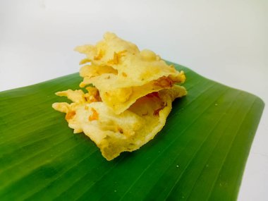 Rempeyek karidesi, geleneksel karidesli Java krakeri, düz bir şekilde kızartılmış. Muz yaprağında servis edilmiş, beyaz arka planda izole edilmiş..