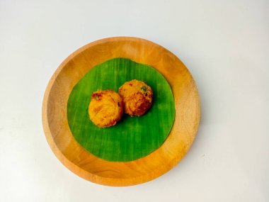 Perkedel Kentang ya da Patates Perkedel, patates püresi, kereviz, baharat ve kızarmış Endonezya yemekleri. Tahta tabakta muz yaprağında servis edilmiş, beyaz arka planda izole edilmiş..