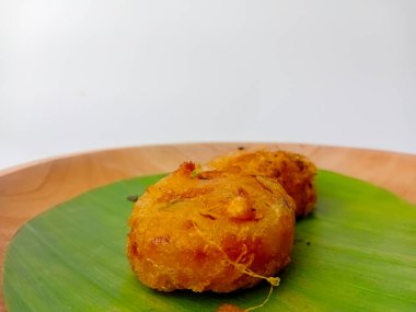 Perkedel Kentang ya da Patates Perkedel, patates püresi, kereviz, baharat ve kızarmış Endonezya yemekleri. Tahta tabakta muz yaprağında servis edilmiş, beyaz arka planda izole edilmiş..