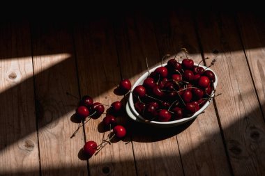 Kiraz. Güneşin ışınları pencereden kirazlı bir tabakta parlıyor.