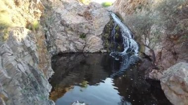 Ukrayna 'nın Maloyanisol bölgesinde katmanlı kaya oluşumlarıyla çevrili karanlık bir havuza düşen tenha bir şelalenin insansız hava aracı görüntüsü. Yüksek kaliteli FullHD görüntüler