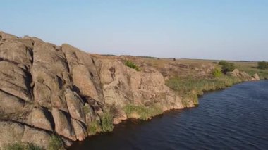 Ukrayna bozkırlarında eski granit kayaları ve yemyeşil nehir kıyıları olan pitoresk bir gölet. Mariupol, Donetsk bölgesi yakınlarındaki Yekaterinovka köyünün doğal güzelliği