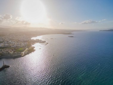Venetian harbour in Chania from drone in clear sunny winter weather, showcasing historic waterfront, lighthouse and Mediterranean coastal scenery.