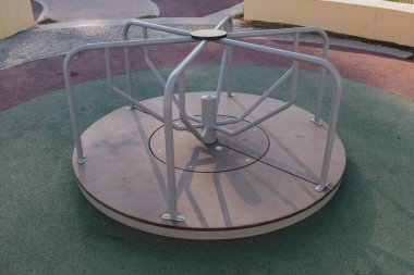 Metal çerçeveli, güneşli ve güvenli bir oyun parkında geleneksel salıncak koltukları. Çocukluk temaları, açık hava eğlencesi ve çocuklar için belirlenmiş güvenli bir alan aktaran huzurlu bir görüntü.