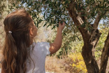 Çocuk, doğayla gençlik arasındaki derin bağlantıyı ve organik çiftçilik kavramını vurgulayan doğal, güneşli bir ortamda yakalanır.