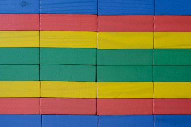 Parlak renkli tahta bloklardan yapılmış bir duvara yakın plan kırmızı, sarı, yeşil ve mavi düzenli geometrik desen ve doku, arka plan için uygun.