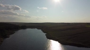 Ukrayna 'nın Maloyanisol köyü yakınlarındaki yuvarlanan tepeler ve tarlalarla çevrili kırsal bir rezervuar ve barajın panoramik drone görüntüsü. Yüksek kaliteli FullHD görüntüler