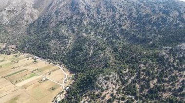 İnsansız hava aracı manzarası: Girit 'in Omalos köyü yakınlarındaki yüksek açılı yaz manzarası. Görüntü, uçsuz bucaksız, bozulmamış doğayı, temiz havayı ve uzak bölgenin dramatik yükselişini vurguluyor.