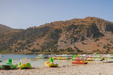 Georgioupoli, Yunanistan. 25 Ekim 2025. Turistler Girit, Kournas Gölü 'nün sakin sularında pedallı tekne kiralamayı seviyorlar. Seyahat, açık hava eğlencesi ve aile tatilleri için ideal.