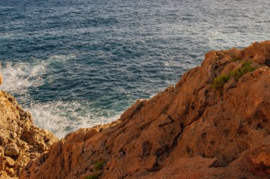 Macera seyahati: Deniz kenarındaki uçurumun parlak güneşli manzarası ve ferahlatıcı turkuaz su. Özgürlüğü, yalnızlığı, yaz tatilini ve egzotik kıyı tatilini çağrıştırıyor..