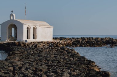 Georgioupolis 'te taş yolu olan sahil şapeli manzaralı Girit çevresindeki deniz ve açık ufukta gün ışığında yakalandı.