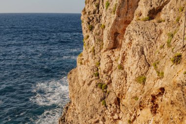 Macera seyahati: Deniz kenarındaki uçurumun parlak güneşli manzarası ve ferahlatıcı turkuaz su. Özgürlüğü, yalnızlığı, yaz tatilini ve egzotik kıyı tatilini çağrıştırıyor..