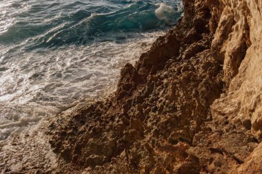 Macera seyahati: Deniz kenarındaki uçurumun parlak güneşli manzarası ve ferahlatıcı turkuaz su. Özgürlüğü, yalnızlığı, yaz tatilini ve egzotik kıyı tatilini çağrıştırıyor..