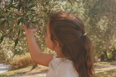 Çocuk, doğayla gençlik arasındaki derin bağlantıyı ve organik çiftçilik kavramını vurgulayan doğal, güneşli bir ortamda yakalanır.