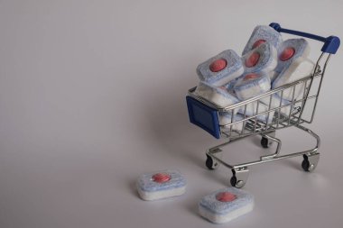 Organize çamaşırlar: bir yığın parlak bulaşık makinesi tabletleri bir tel alışveriş arabasında. Bu fotoğraf ev düzenini ve temizlik malzemelerinin bolluğunu vurguluyor. Düzenli günlük içeriği için uygundur