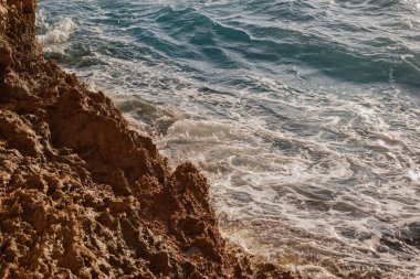 Macera seyahati: Deniz kenarındaki uçurumun parlak güneşli manzarası ve ferahlatıcı turkuaz su. Özgürlüğü, yalnızlığı, yaz tatilini ve egzotik kıyı tatilini çağrıştırıyor..